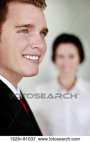 Business man in black suit and red tie smiles as woman in white clothes stands behind him View Large Photo Image Stock Photo - Business man in black suit and red tie smiles as woman in white clothes stands behind him. Fotosearch