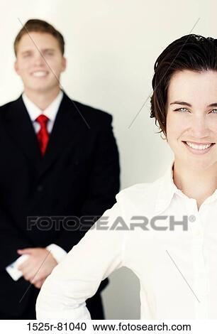 Business man in black suit and tie stands behind smiling woman in white clothes View Large Photo Image Stock Image - Business man in black suit and tie stands behind smiling woman in white clothes. Fotosearch