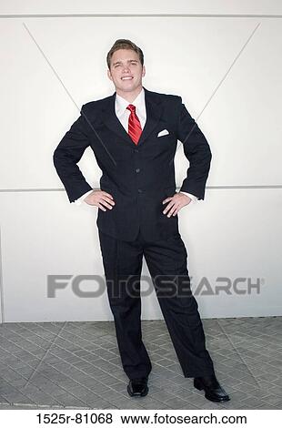 Business man in red tie and black suit standing in dynamic pose against a metallic background View Large Photo Image Stock Photo - Business man in red tie and black suit standing in dynamic pose against a metallic background. Fotosearch