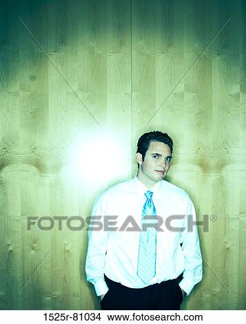 Picture - Business man in white shirt and blue tie stands in front of wood background. Fotosearch