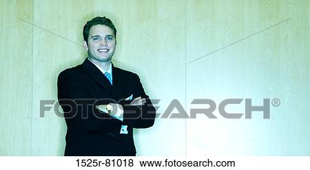 Business Man stands in front of a wood wall with his arms folded and with a smile View Large Photo Image Stock Photo - Business Man stands in front of a wood wall with his arms folded and with a smile. Fotosearch