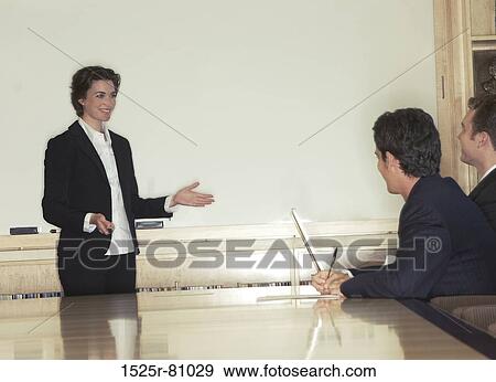 Business woman giving a presentation in a board room with her arms open explaining View Large Photo Image Stock Photo - Business woman giving a presentation in a board room with her arms open explaining. Fotosearch