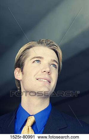 Businessman looks ahead and smiles as he looks up View Large Photo Image Stock Image - Businessman looks ahead and smiles as he looks up. Fotosearch