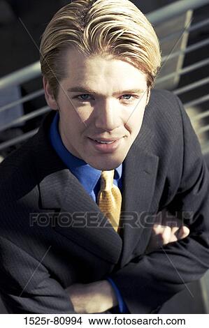 Businessman looks up and smiles into the camera with his arms folded View Large Photo Image Picture - Businessman looks up and smiles into the camera with his arms folded. Fotosearch