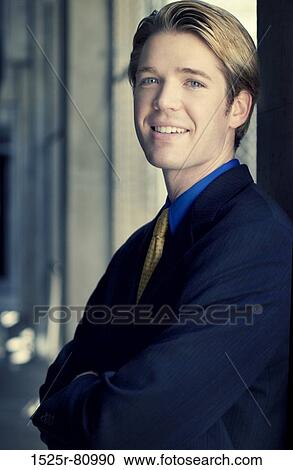 Businessman smiles and stands against the wall View Large Photo Image Stock Image - Businessman smiles and stands against the wall. Fotosearch