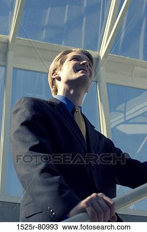 Businessman stands on the railing and looks up with vision View Large Photo Image Stock Image - Businessman stands on the railing and looks up with vision. Fotosearch