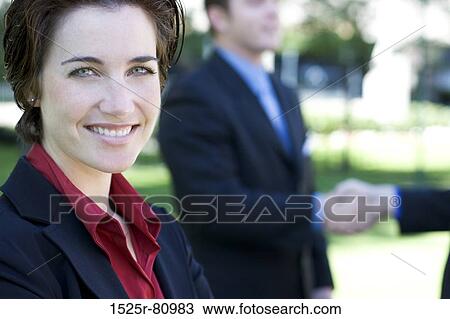 Businesswoman smiles and looks ahead while two businessmen shake hands View Large Photo Image Stock Image - Businesswoman smiles and looks ahead while two businessmen shake hands. Fotosearch