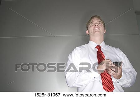 Low angle view of a businessman operating a personal data assistant View Large Photo Image Stock Photo - Low angle view of a businessman operating a personal data assistant. Fotosearch