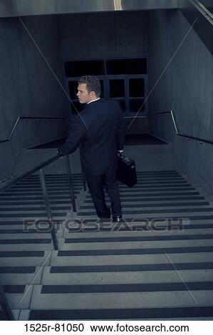 Stock Image - Rear view of a businessman moving down a staircase. Fotosearch