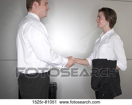Stock Image - Side profile of a businessman and a businesswoman shaking hands. Fotosearch