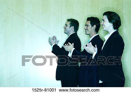 Three Business people clap together while facing in the same direction in front of a wood background View Large Photo Image Stock Image - Three Business people clap together while facing in the same direction in front of a wood background. Fotosearch