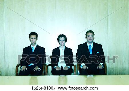 Three business people sitting together and facing ahead behind a conference table View Large Photo Image Stock Photo - Three business people sitting together and facing ahead behind a conference table. Fotosearch