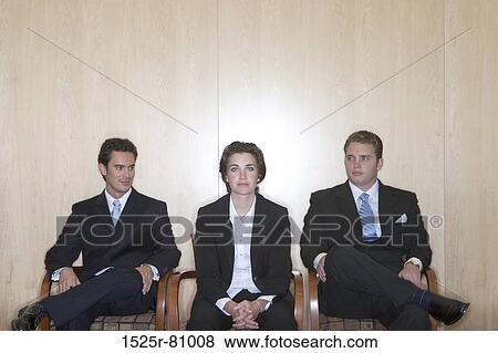 Three business people sitting with the business woman sitting in the middle and the two business men looking at her View Large Photo Image Stock Photo - Three business people sitting with the business woman sitting in the middle and the two business men looking at her. Fotosearch