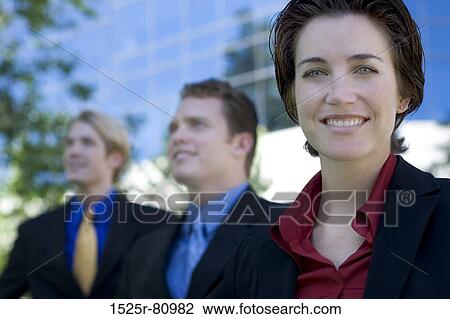 Three business people stand together while the businesswoman smiles and looks ahead View Large Photo Image Stock Image - Three business people stand together while the businesswoman smiles and looks ahead. Fotosearch