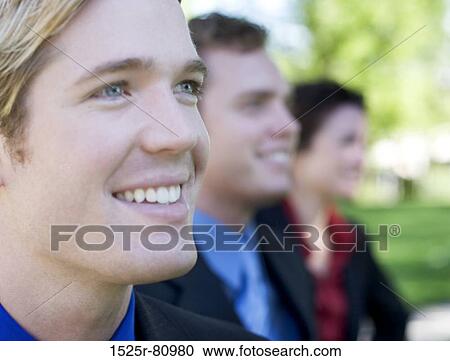 Three businesspeople standing together looking ahead and smiling View Large Photo Image Stock Image - Three businesspeople standing together looking ahead and smiling. Fotosearch