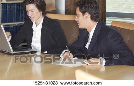 Stock Photo - Two Business People discussing their work with a laptop in the board room. Fotosearch
