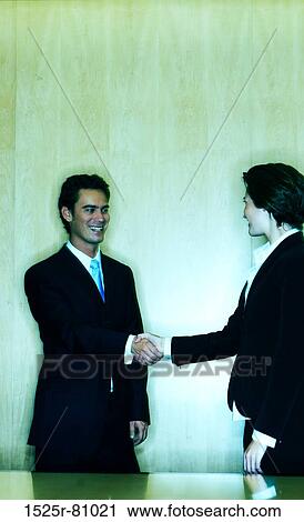 Two Business people shake hands with smiles in front of a wood background View Large Photo Image Stock Image - Two Business people shake hands with smiles in front of a wood background. Fotosearch