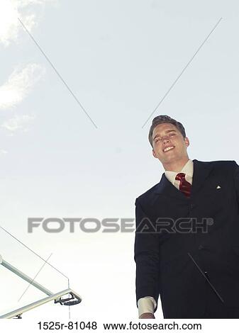Younger business man in black suit and red tie smiles as he stands holding his briefcase walking down steps View Large Photo Image Stock Photo - Younger business man in black suit and red tie smiles as he stands holding his briefcase walking down steps. Fotosearch