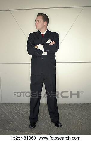 Younger business man in black suit in red tie standing in dynamic pose in front of metallic background View Large Photo Image Stock Photo - Younger business man in black suit in red tie standing in dynamic pose in front of metallic background. Fotosearch