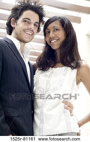 Stock Image - Close-up of a young couple embracing each other and smiling. Fotosearch