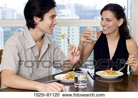 Close-up of a young couple sitting at a dining table View Large Photo Image Stock Image - Close-up of a young couple sitting at a dining table. Fotosearch