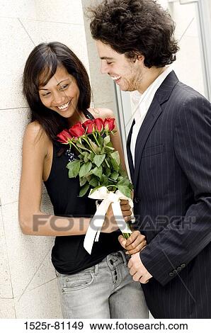 Close-up of a young man giving a bouquet of roses to a young woman View Large Photo Image Stock Photo - Close-up of a young man giving a bouquet of roses to a young woman. Fotosearch