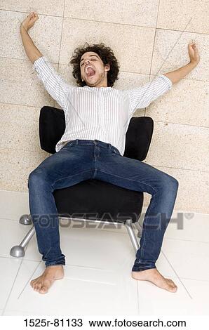 Close-up of a young man sitting in a chair and stretching View Large Photo Image Stock Image - Close-up of a young man sitting in a chair and stretching. Fotosearch