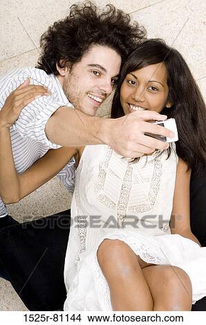 Close-up of a young man taking a picture of himself and a young woman with a mobile phone View Large Photo Image Picture - Close-up of a young man taking a picture of himself and a young woman with a mobile phone. Fotosearch
