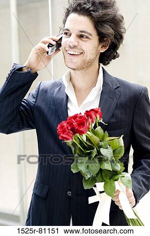Close-up of a young man talking on a mobile phone and holding a bouquet of roses View Large Photo Image Stock Image - Close-up of a young man talking on a mobile phone and holding a bouquet of roses. Fotosearch