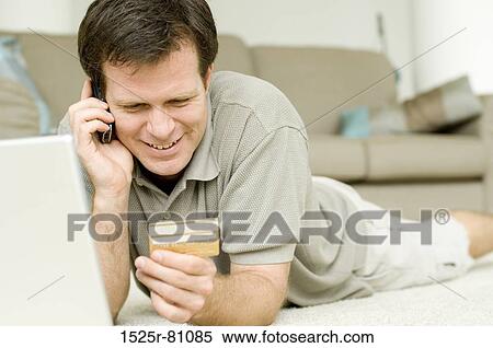 Close-up of a young man talking on a mobile phone and holding a credit card View Large Photo Image Stock Photography - Close-up of a young man talking on a mobile phone and holding a credit card. Fotosearch