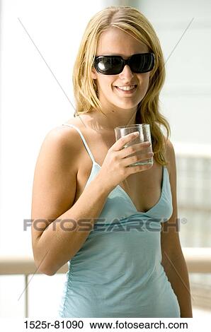 Close-up of a young woman holding a glass and smiling View Large Photo Image Stock Image - Close-up of a young woman holding a glass and smiling. Fotosearch