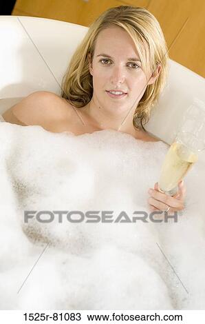Portrait of a young woman holding a champagne flute in a bathtub View Large Photo Image Stock Image - Portrait of a young woman holding a champagne flute in a bathtub. Fotosearch