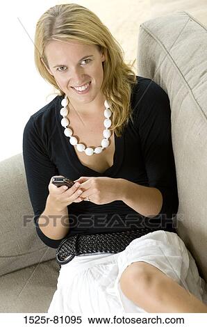 Portrait of a young woman holding a mobile phone and smiling View Large Photo Image Stock Photography - Portrait of a young woman holding a mobile phone and smiling. Fotosearch