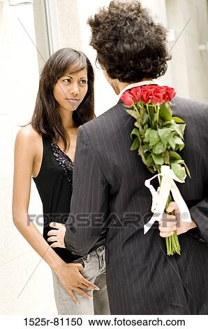 Rear view of a young man hiding bouquet of roses from a young woman View Large Photo Image Stock Image - Rear view of a young man hiding bouquet of roses from a young woman. Fotosearch