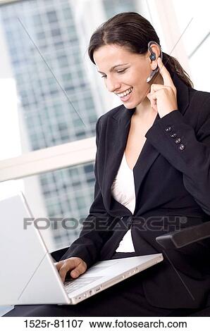 Stock Photo - Side profile of a businesswoman using a laptop and smiling. Fotosearch