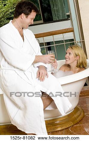 Side profile of a young couple toasting with champagne in the bathroom View Large Photo Image Stock Image - Side profile of a young couple toasting with champagne in the bathroom. Fotosearch