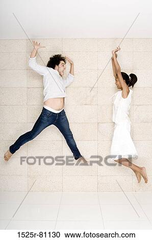 Young couple jumping with arms raised View Large Photo Image Stock Image - Young couple jumping with arms raised. Fotosearch