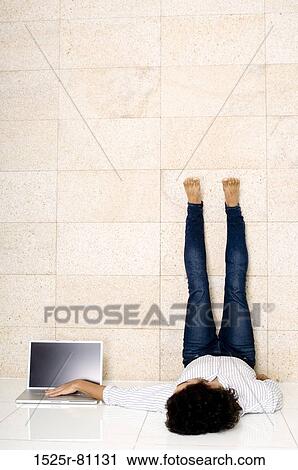 Young man lying on the floor near a laptop View Large Photo Image Stock Image - Young man lying on the floor near a laptop. Fotosearch
