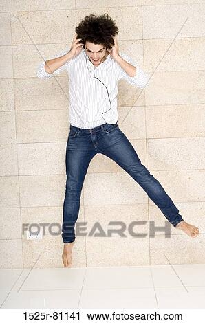 Young man wearing headphones and jumping View Large Photo Image Stock Image - Young man wearing headphones and jumping. Fotosearch