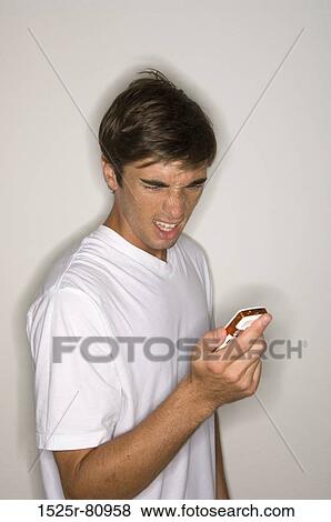 Close-up of a young man looking at a mobile phone View Large Photo Image Stock Photo - Close-up of a young man looking at a mobile phone. Fotosearch