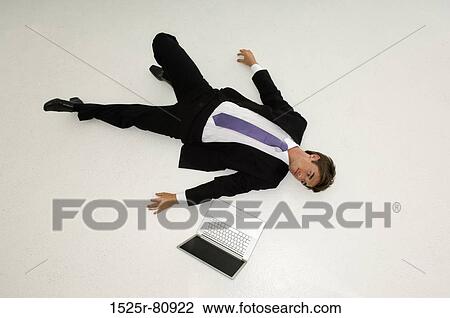 High angle view of a young man lying on the floor with a laptop beside him View Large Photo Image Stock Image - High angle view of a young man lying on the floor with a laptop beside him. Fotosearch