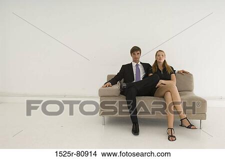 Portrait of a young couple sitting on a couch View Large Photo Image Picture - Portrait of a young couple sitting on a couch. Fotosearch