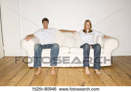 Portrait of a young couple sitting on a couch View Large Photo Image Stock Photograph - Portrait of a young couple sitting on a couch. Fotosearch