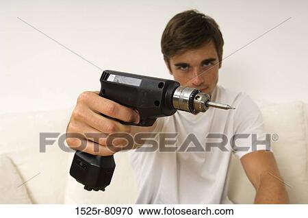 Portrait of a young man holding a drill View Large Photo Image Stock Image - Portrait of a young man holding a drill. Fotosearch