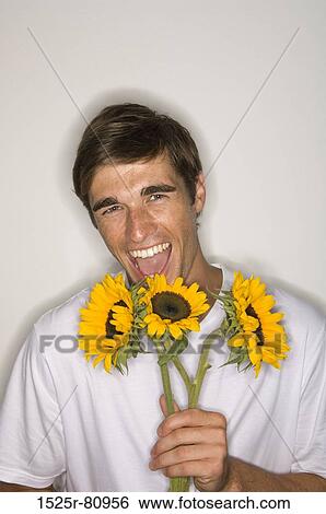 Portrait of a young man holding sunflowers and laughing View Large Photo Image Stock Photograph - Portrait of a young man holding sunflowers and laughing. Fotosearch
