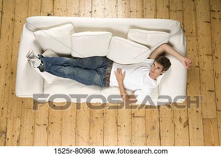 Portrait of a young man lying on a couch View Large Photo Image Stock Photo - Portrait of a young man lying on a couch. Fotosearch