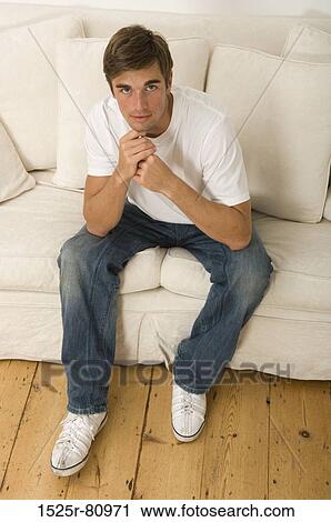 Portrait of a young man sitting on a couch View Large Photo Image Stock Image - Portrait of a young man sitting on a couch. Fotosearch