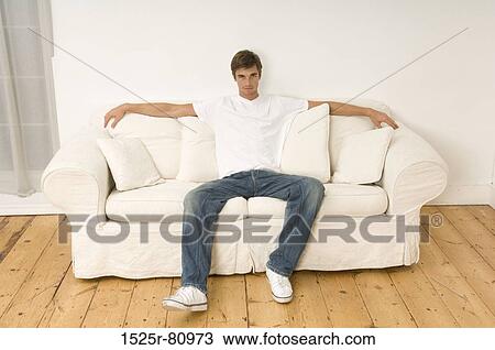 Portrait of a young man sitting on a couch View Large Photo Image Stock Image - Portrait of a young man sitting on a couch. Fotosearch