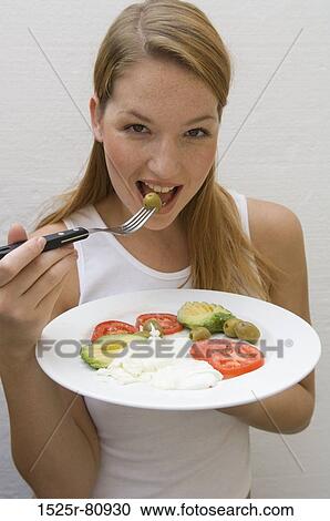 Portrait of a young woman eating an olive with a fork View Large Photo Image Stock Image - Portrait of a young woman eating an olive with a fork. Fotosearch