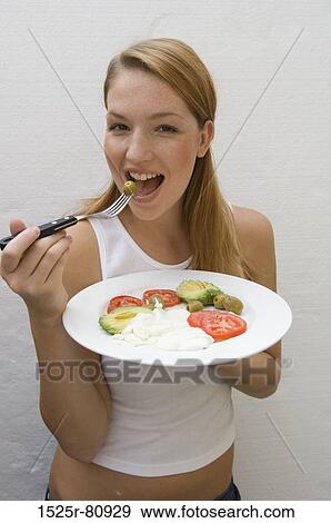 Portrait of a young woman eating an olive with a fork View Large Photo Image Stock Photo - Portrait of a young woman eating an olive with a fork. Fotosearch